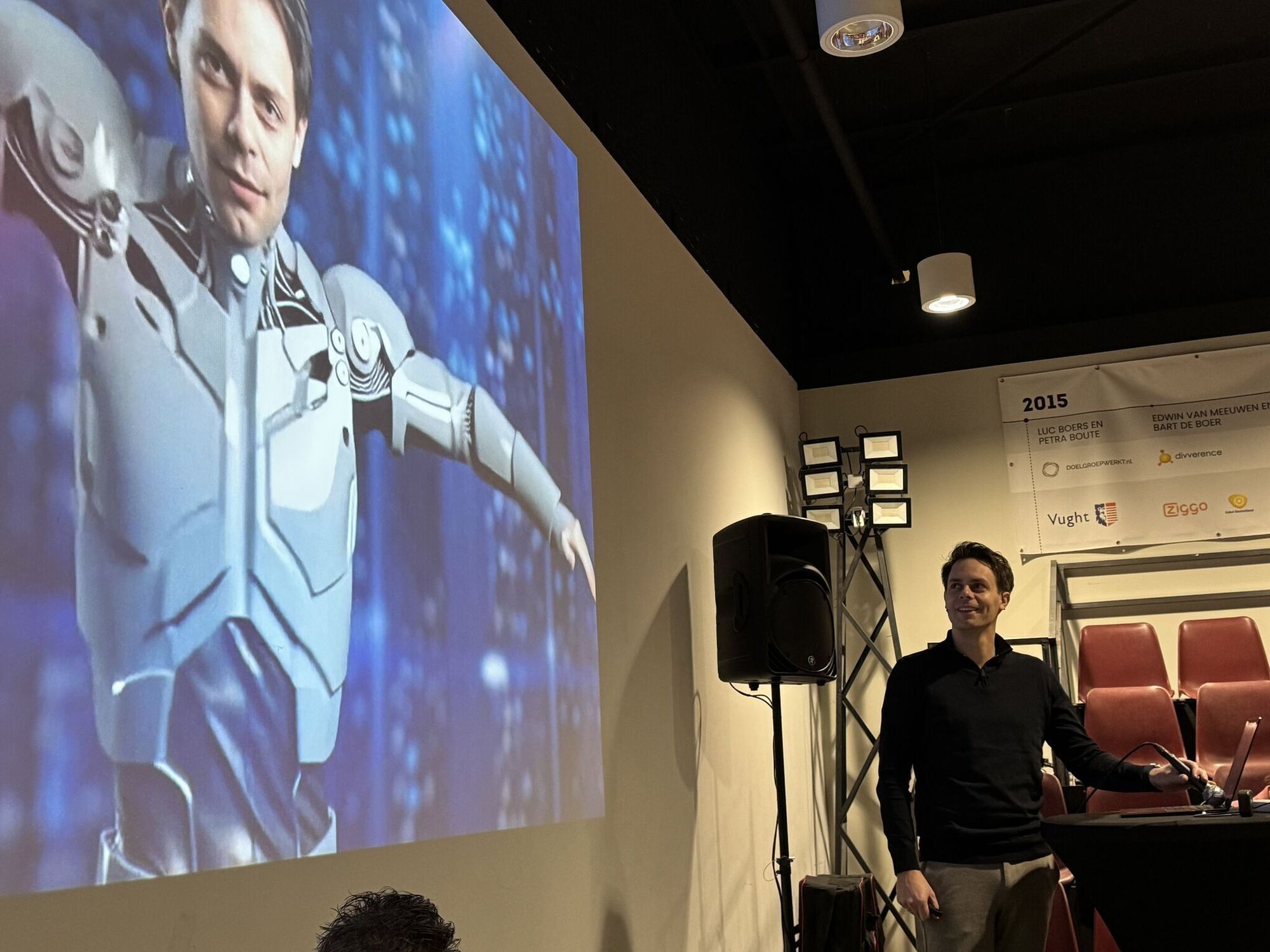 Bo op het podium, met zijn AI-dubbelganger op het scherm